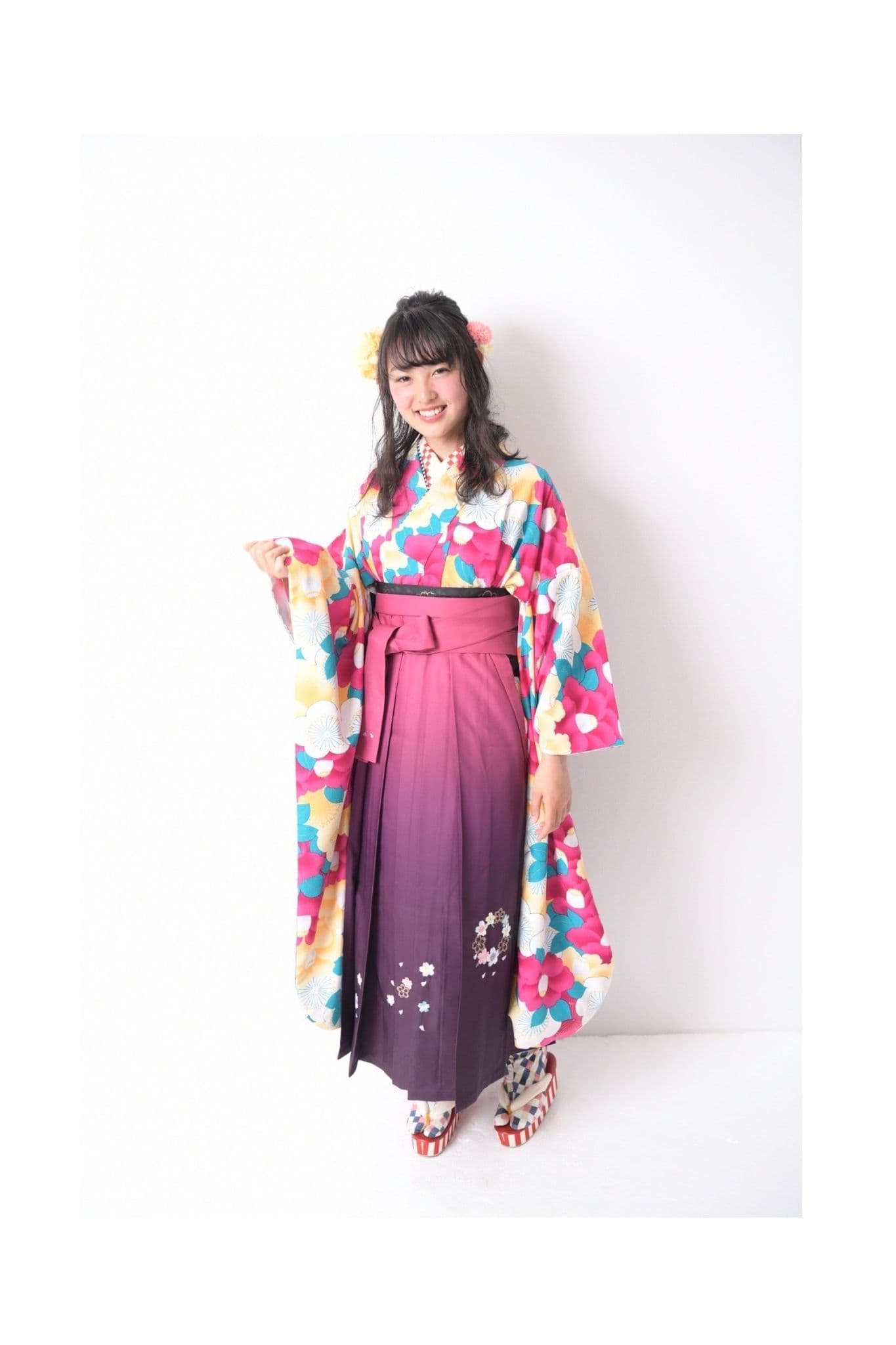 大柄の花の着物とピンクと紫のグラデーションの袴を着た若い女性